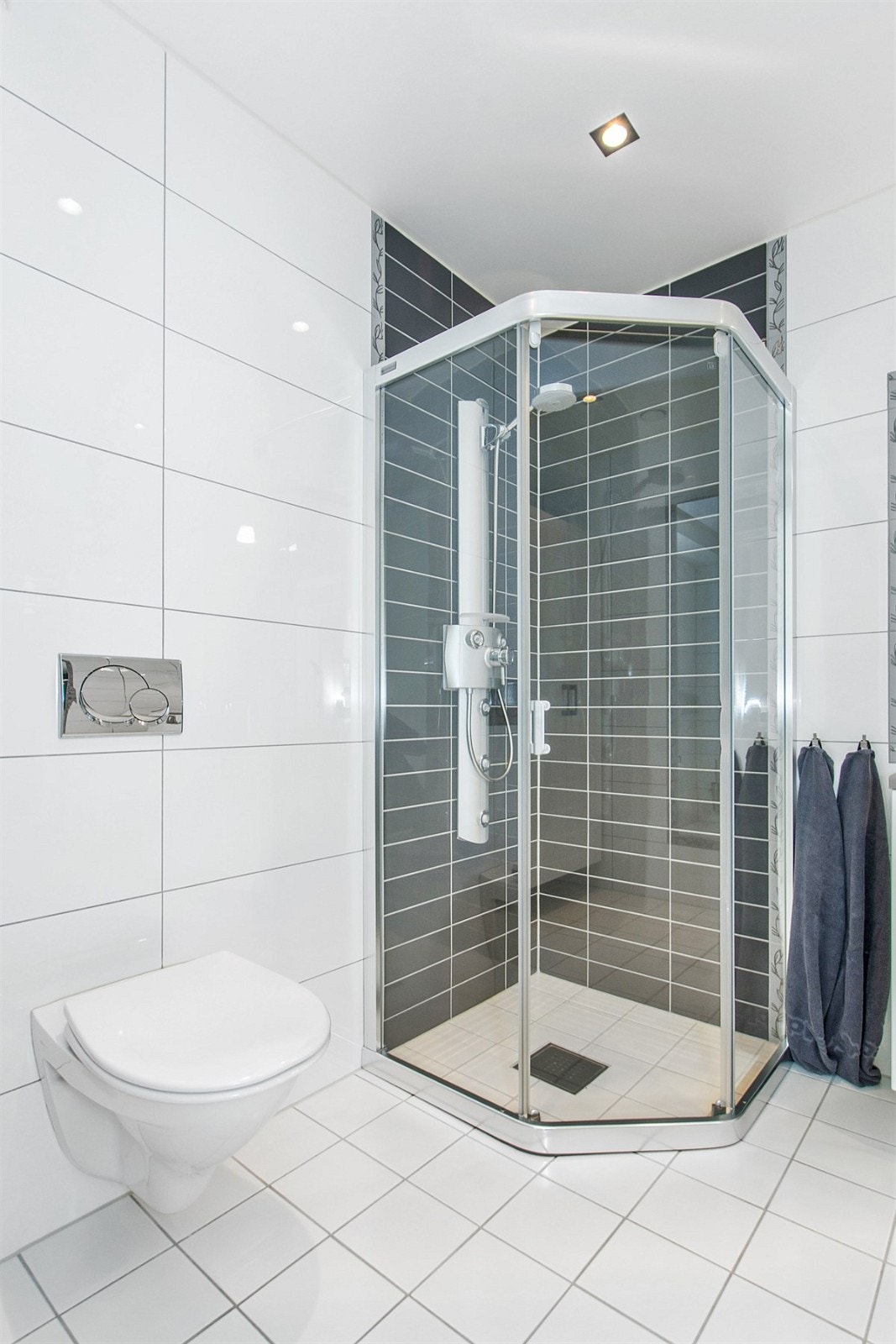 Badet i sokkeletasje er på ca. 5m², og er effektivt utnyttet med dusjhjørne, vegghengt toalett og servant med over- og underskap.. Galleribilde