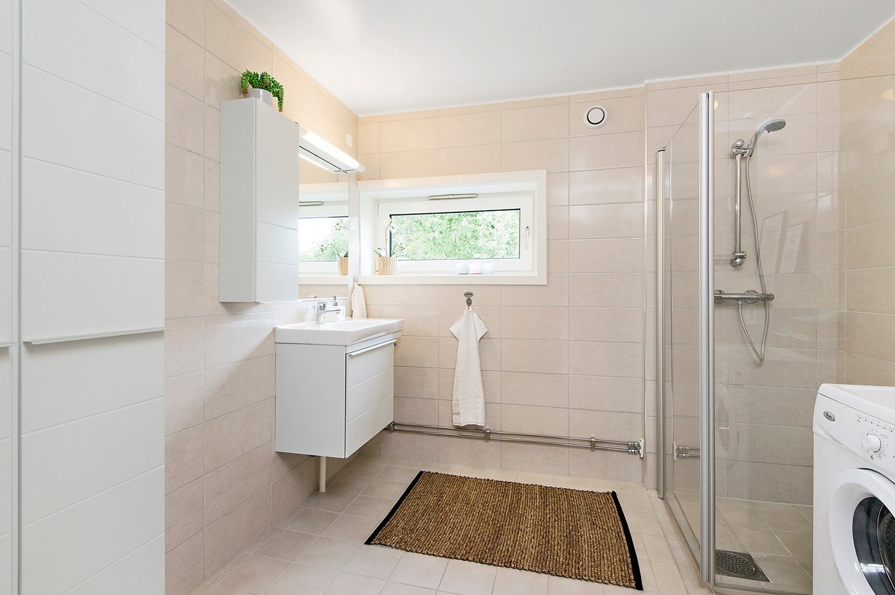 Romslig bad med dusjhjørne og opplegg vaskemaskin Galleribilde