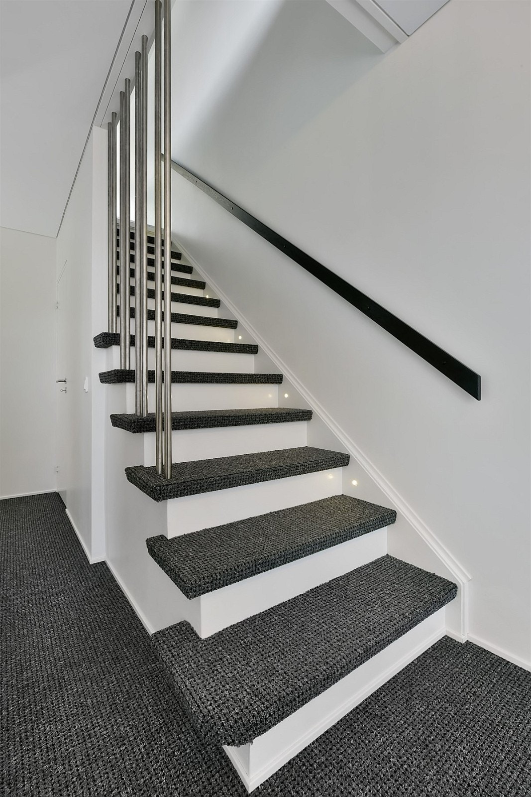 Elegant, teppebelagt trapp med stålspiler og innfelt belysning. Galleribilde