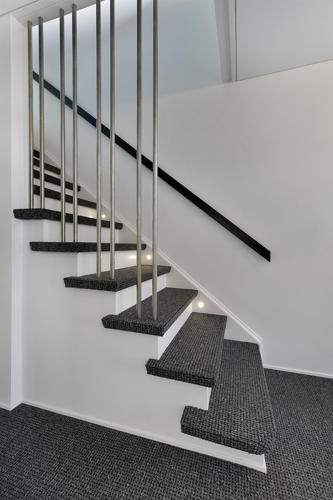 Elegant, teppebelagt trapp med stålspiler og innfelt belysning. Galleribilde