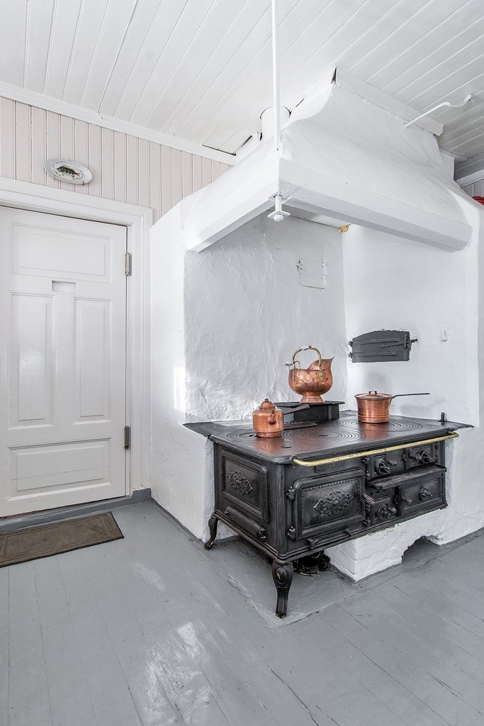 Kjøkkenet har en vedovn med store kokeplater Galleribilde