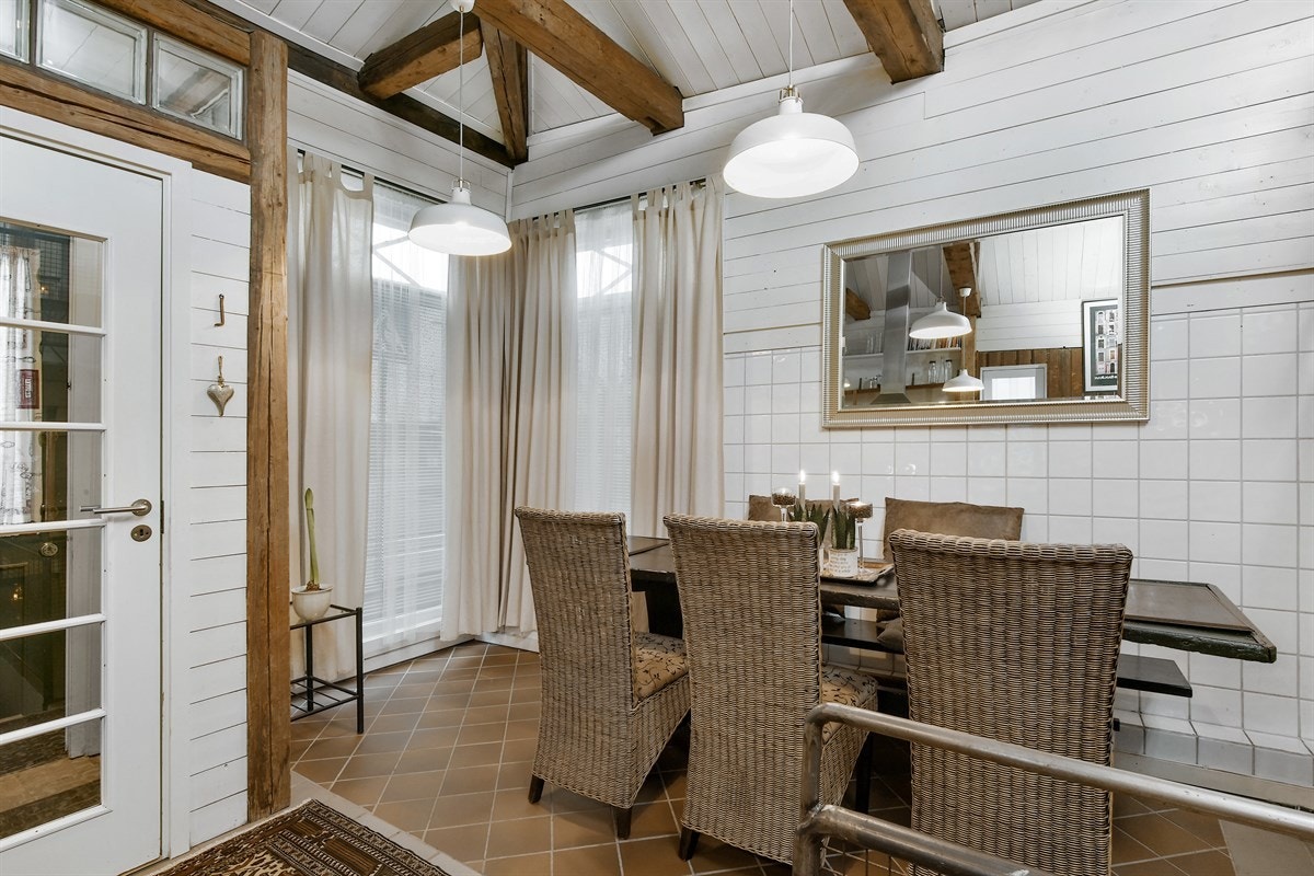 Rommet har ellers synlige bjelker i tak og på vegger, ekstra takhøyde, god plass for spisestuemøbler, samt direkte utgang til bakgård. Galleribilde