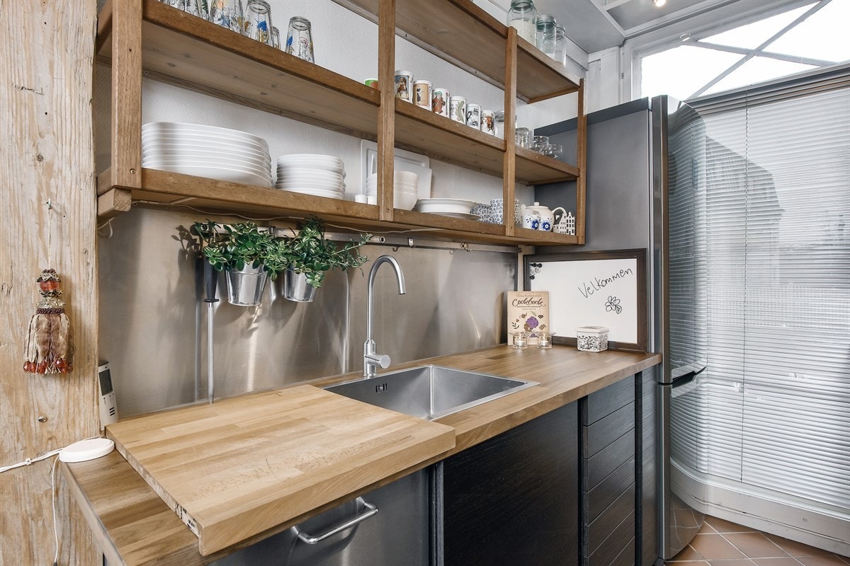 Det er stålplate, belysning og åpne hyller over benk, samt opplegg for oppvaskmaskin under benk. Galleribilde