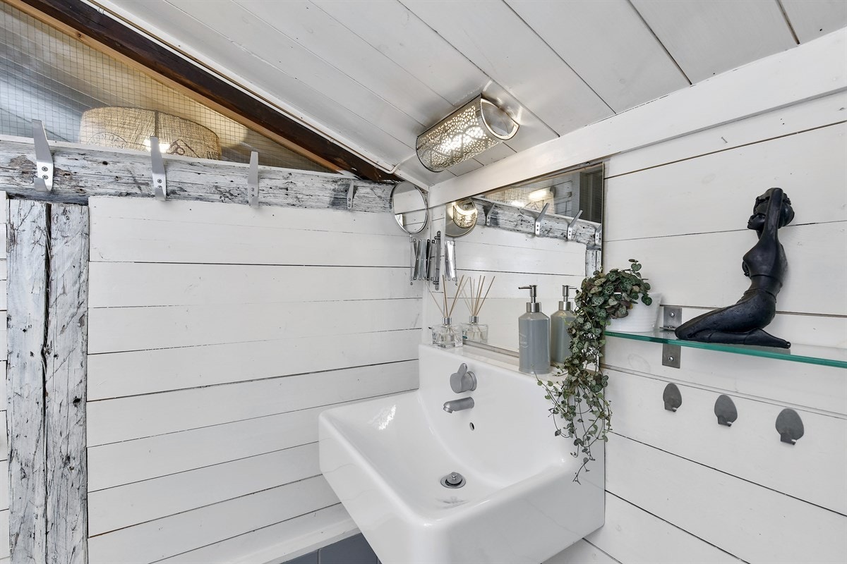 Her er det lysegrå fliser på gulv med gulvvarme, samt hvite fliser og trepanel på vegg. Galleribilde