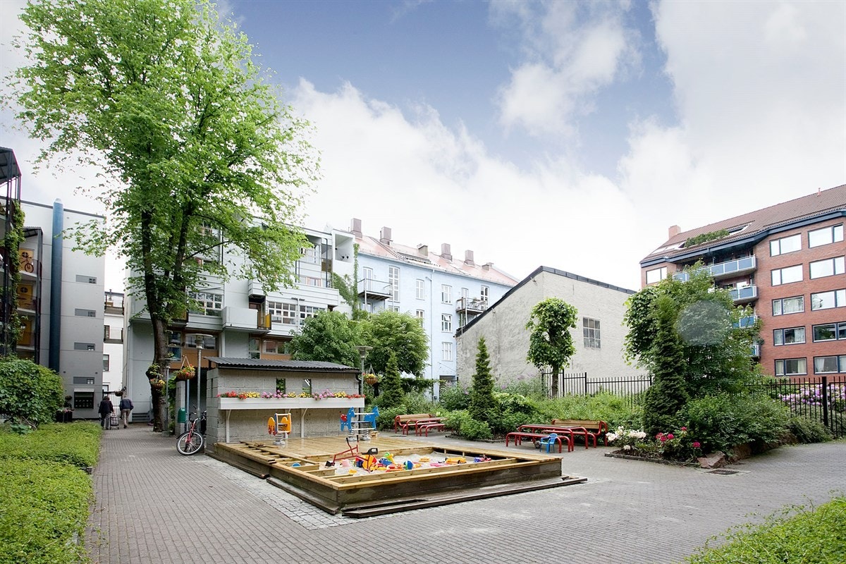 Bakgården med beplantning og hyggelig lekeplass med sandkasse Galleribilde