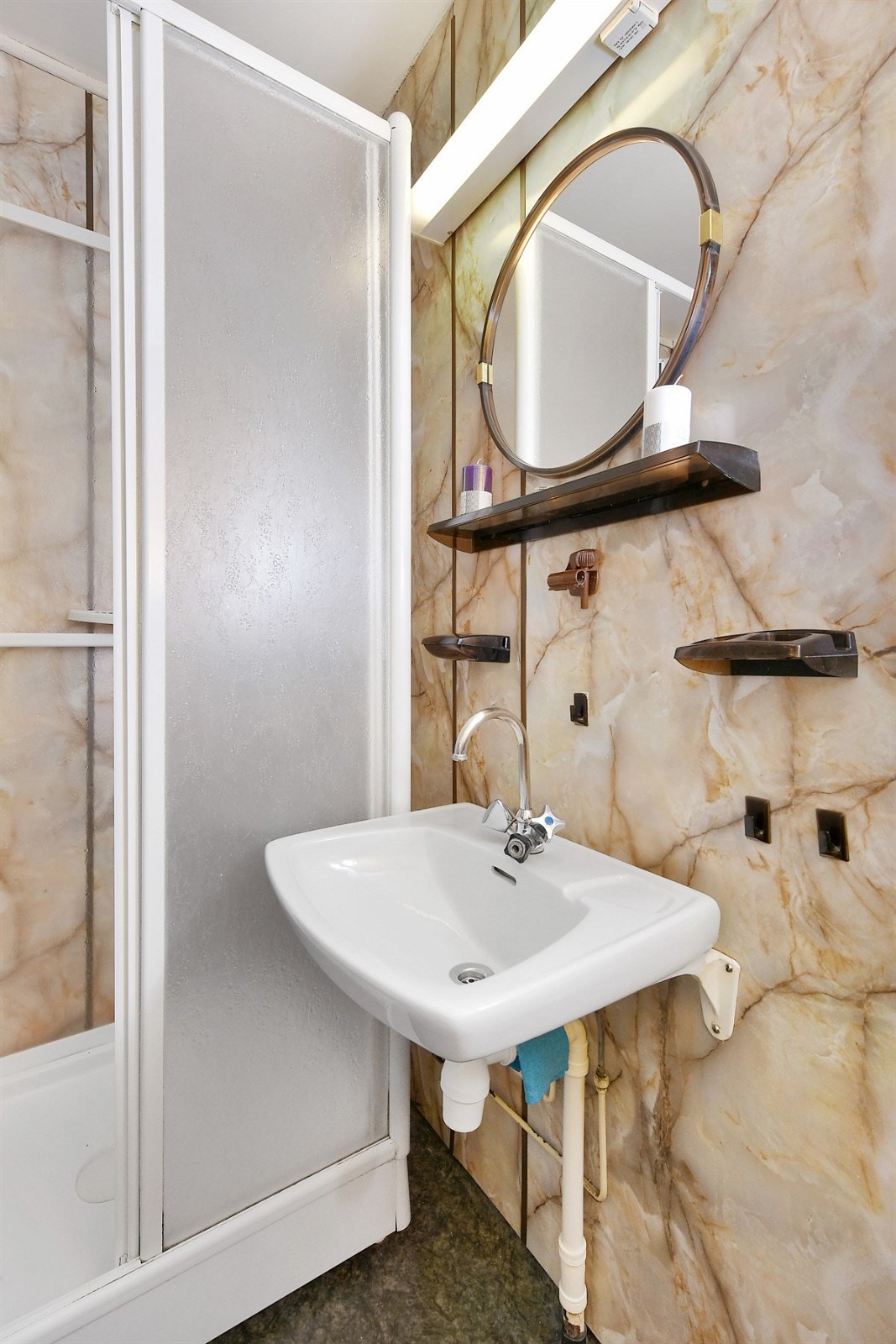 Badet har våtromsplater på vegg og våtromsbelegg på gulv. Videre er det gulvvarme, servant, speil med overbelysning, speilskap og dusjkabinett med skyvedører. Galleribilde