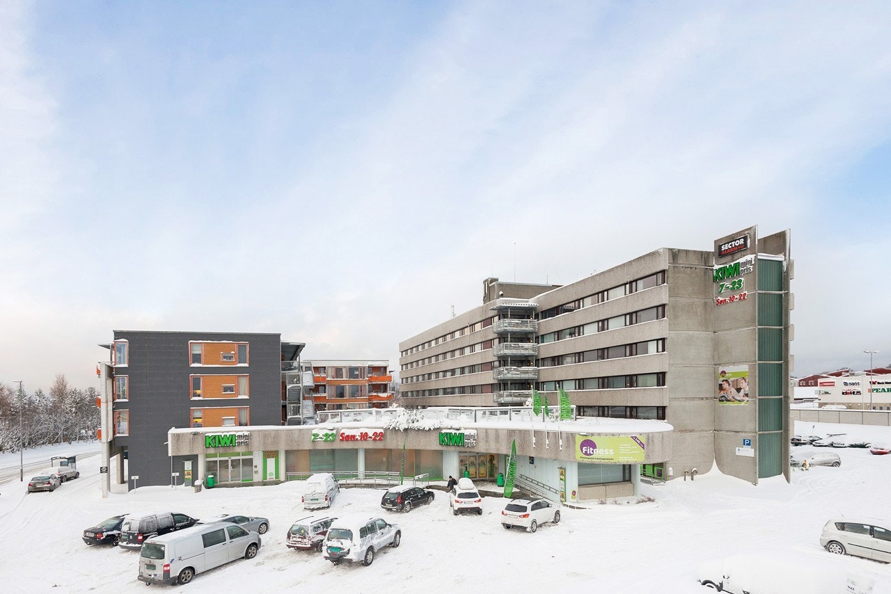 Leiligheten ligger vegg i vegg med Kiwibutikk og over gaten finner man Bohus med kafe, baker og Rema 1000 Galleribilde