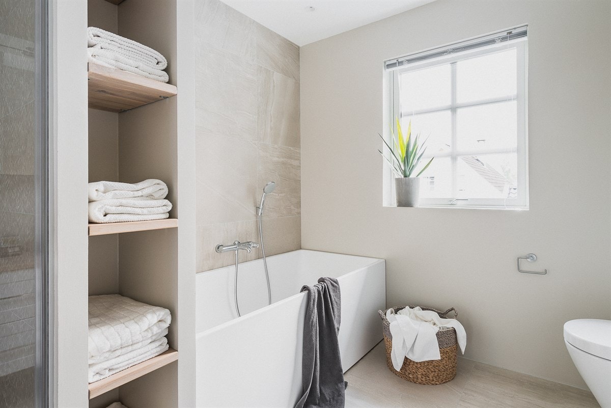 Svært store, kvadratiske fliser gir gulvet et røft utseende og er videreført på én vegg bak badekaret, som i seg selv er et elegant element i rommet. Galleribilde