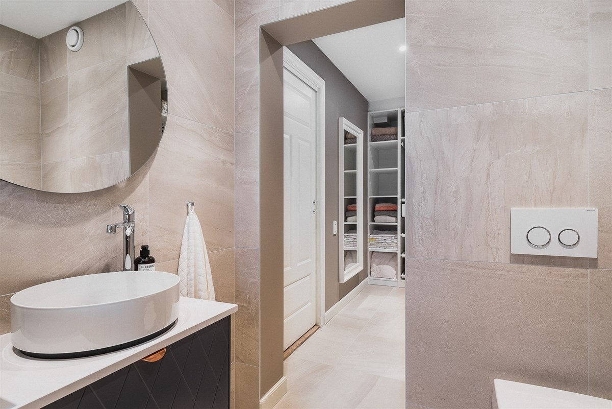 Via garderoben tar du deg inn til badet, der gulv og vegger er belagt med eksklusive fliser og innredningen for øvrig er fra de samme kvalitetsprodusentene som på badet under. Galleribilde