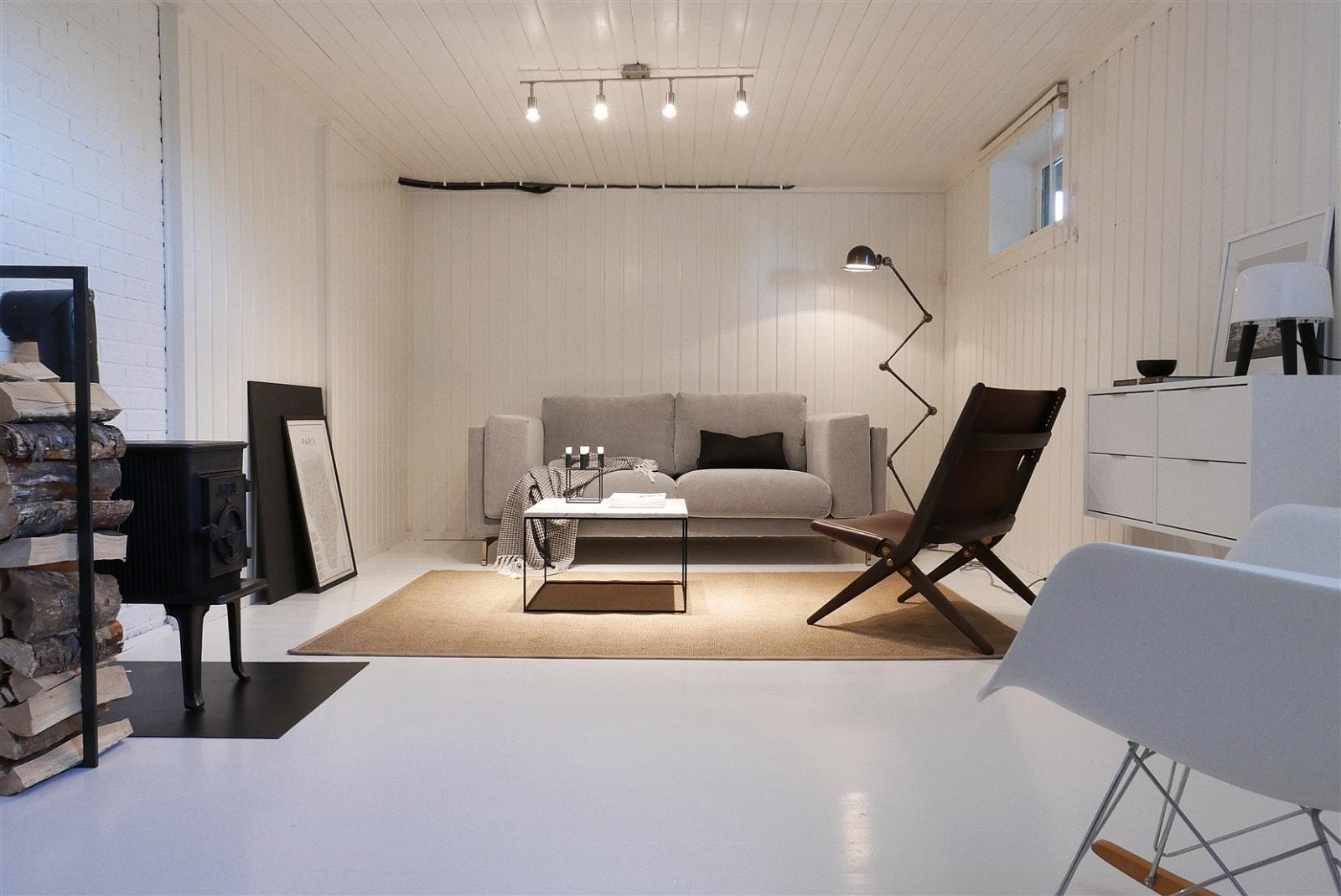 Koselig stue i kjelleren med lyse overflater og vedovn. Galleribilde