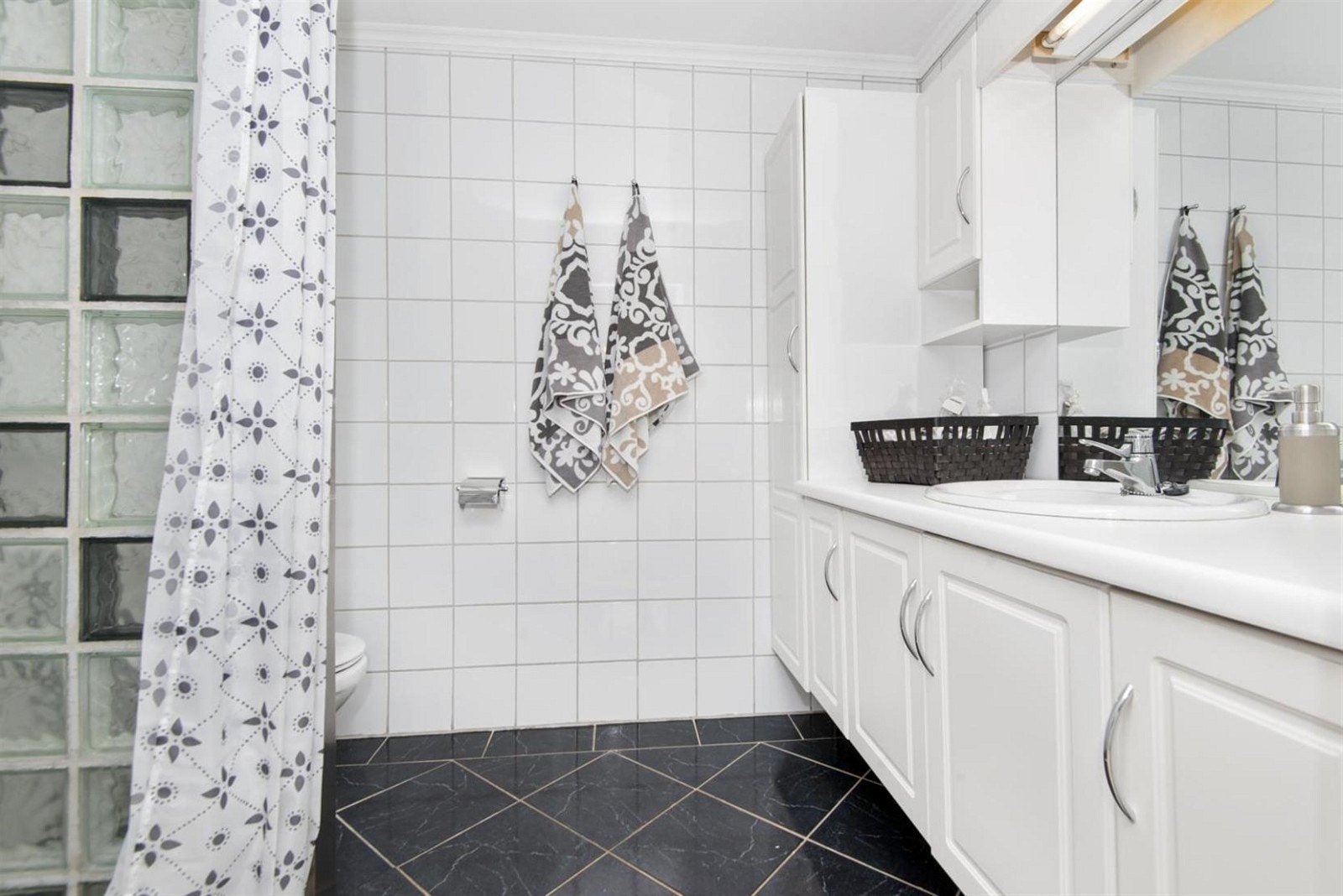 Badet i første etasje med dusjvegg i glassbyggestein og forøvrig fliselagt. Galleribilde