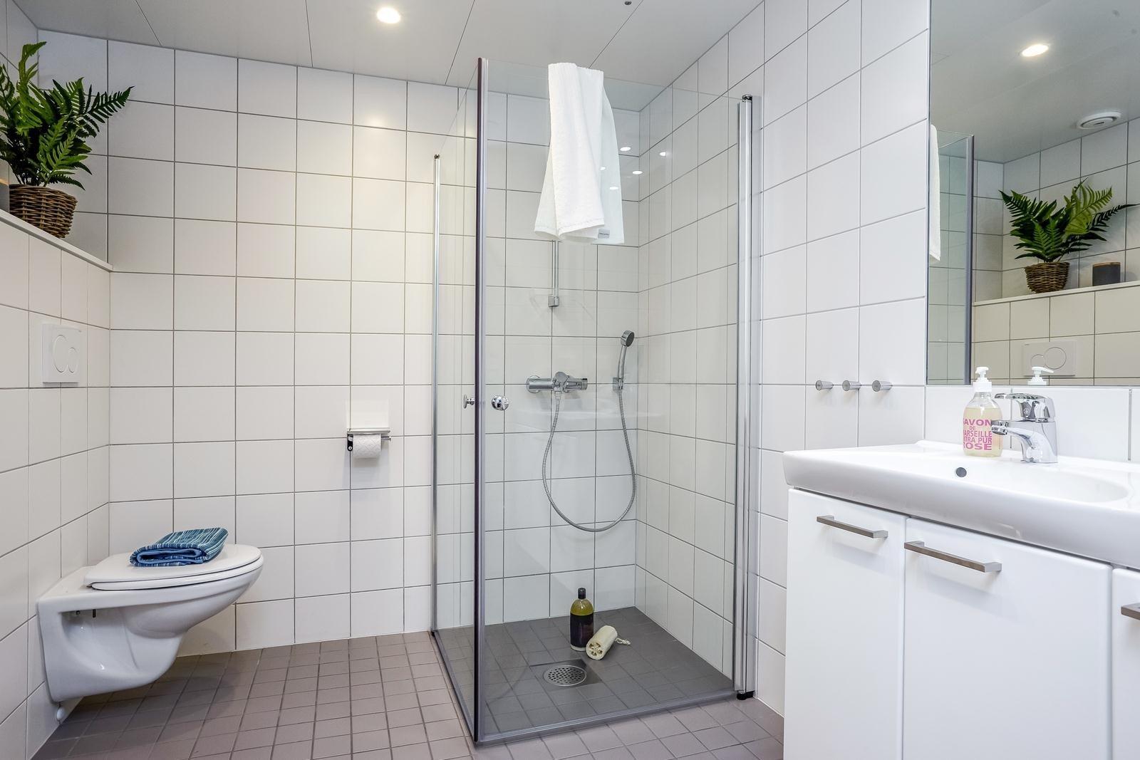 Lekkert, flisbelagt bad med mørkt gulv og hvite vegger Galleribilde