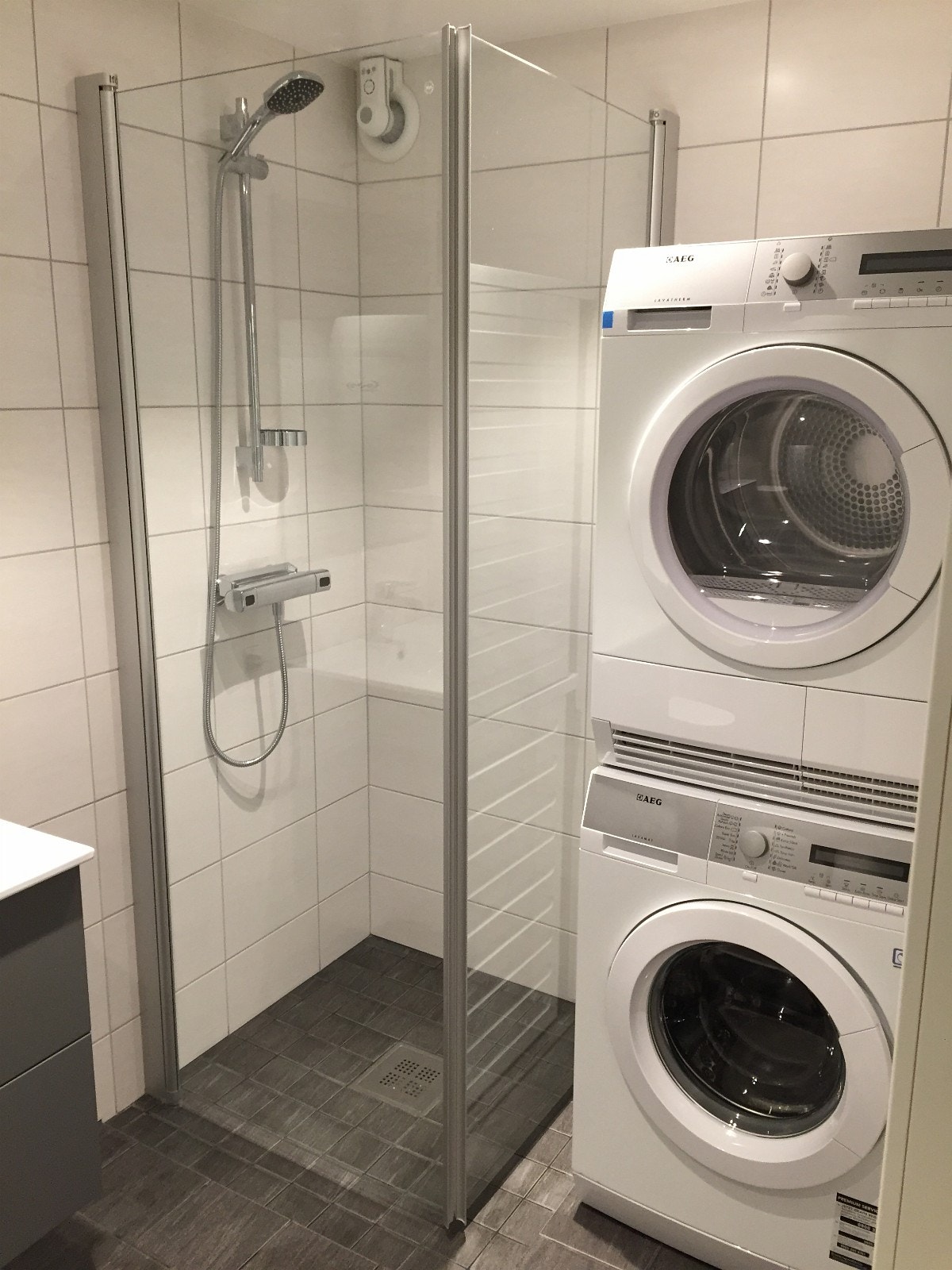Flislagt vaskerom med 80 x 80 cm dusjhjørne, vaskemaskin og tørketrommel. Galleribilde