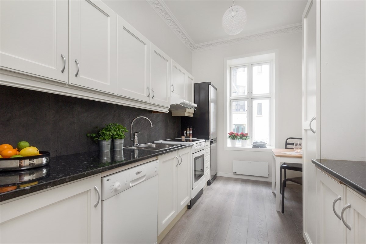 Tidløs kjøkkeninnredning i hvite profilerte fronter og laminat benkeplate. Galleribilde