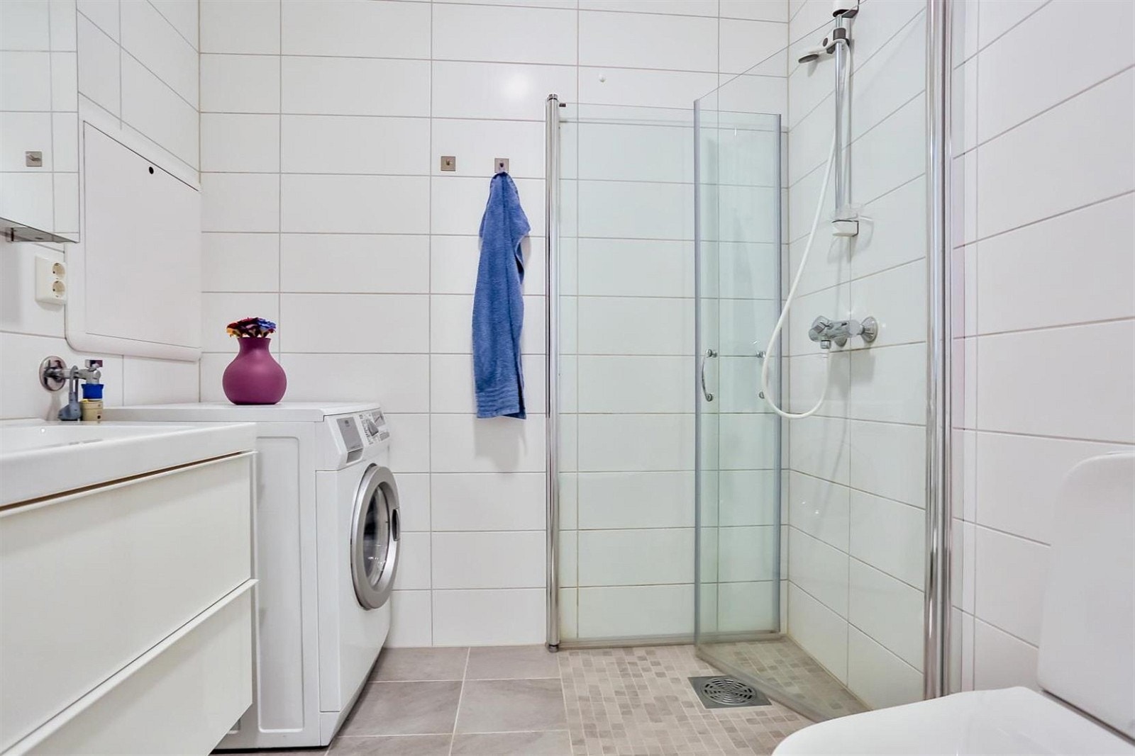 Badet er flislagt med lekre fliser og har praktisk dusjhjørne med innfellbare dører Galleribilde