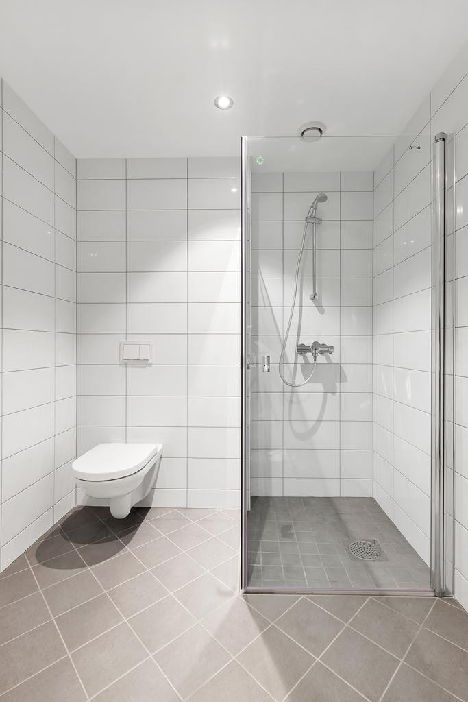 Dusjnisje og vegghengt toalett. Flis på gulv og vegger. Galleribilde