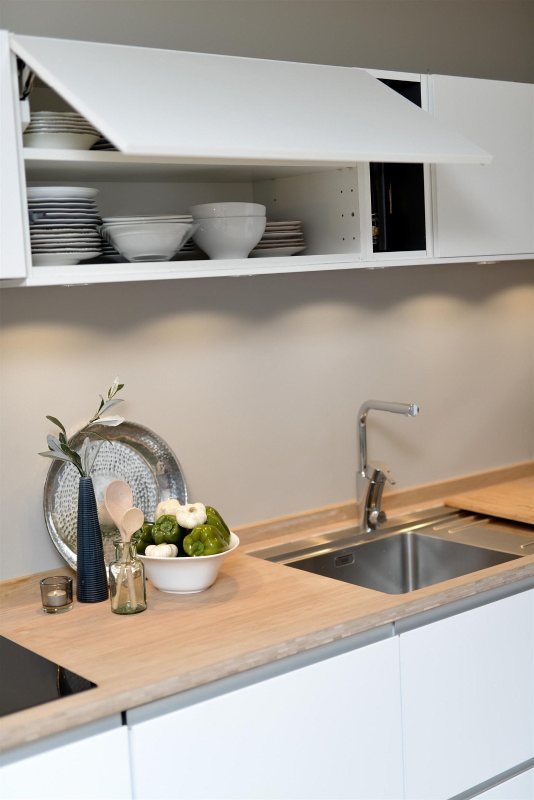 Kjøkkeninnredning med glatte folierte fronter, bambus benkeplate og integrerte hvitevarer. Galleribilde