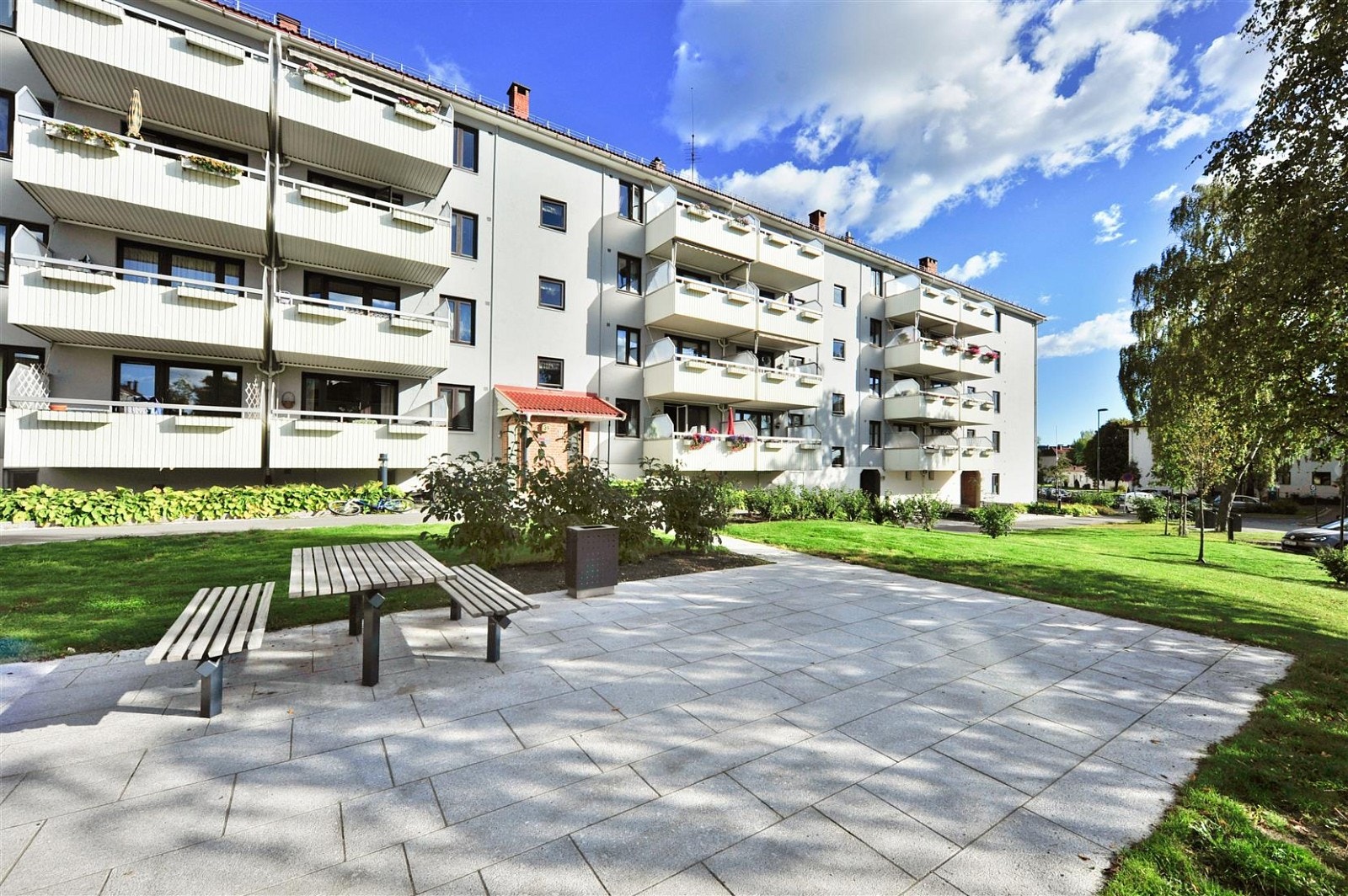 Pent opparbeidet fellesareal med blant annet sittegrupper, gressplener, trær og prydbusker Galleribilde