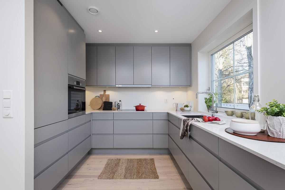 Eksklusiv kjøkkeninnredning med glatte grå fronter uten håndtak som gir en stilren og ryddig følelse Galleribilde