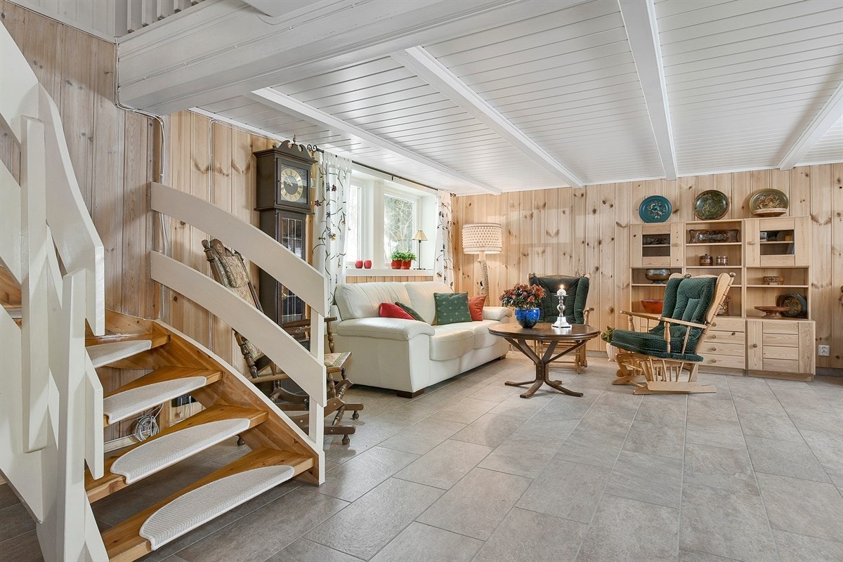 Kjellerstuen er hyggelig og romslig med nyere fliser på gulv, panelte vegger og store vinduer godkjent som rømningsvindu. Galleribilde