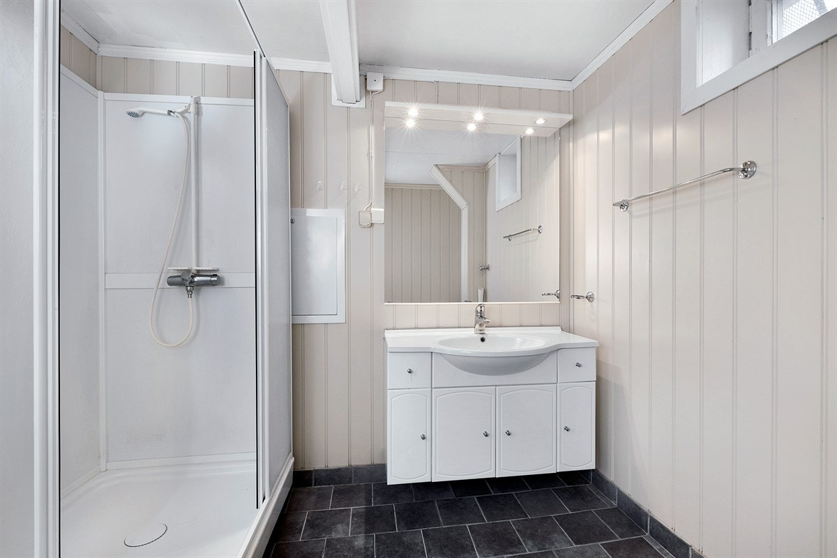 Det andre badet tilhører utleiedelen og har fliser på gulv med underliggende gulvvarme. For øvrig er det panelte vegger i dus farge. Galleribilde