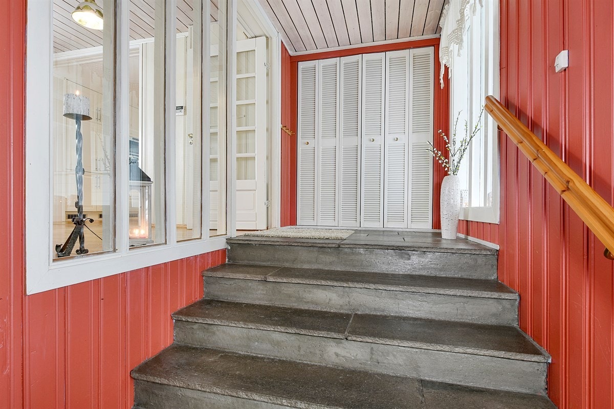 Fra et overbygd inngangsparti kommer du inn til et trapperepos med skiferfliser, gulvvarme, åpen garderobeløsning og garderobeskap. Galleribilde