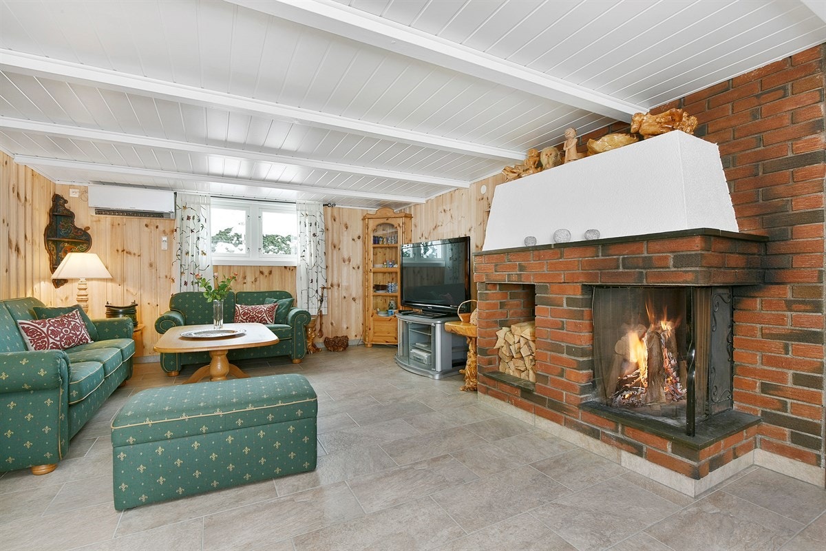 Hjemmekoslig kjellerstue med god varme fra peis, perfekt for filmkvelder. Galleribilde