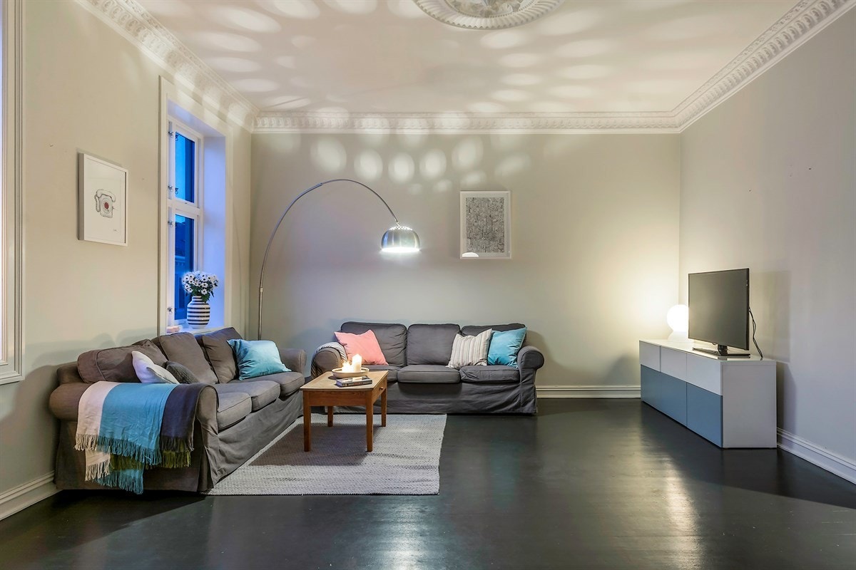 Stuen oppleves som luftig og tiltalende med ekstra takhøyde, velholdt, bred stukkatur og dekorativ rosett i himling. Galleribilde