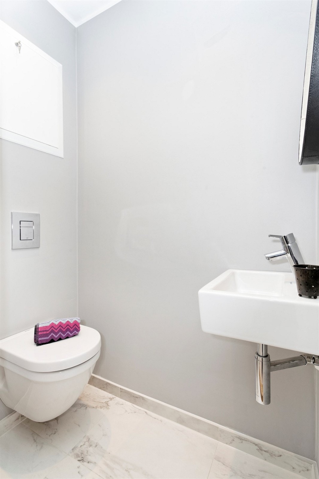 Toalettrommet har veggmontert toalett, servant og marmorfliser på gulv med varmekabler. Galleribilde