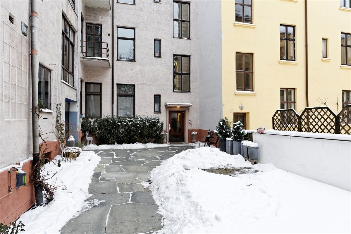 Hyggelig steinbelagt bakgård med prydbusker og planter. Galleribilde