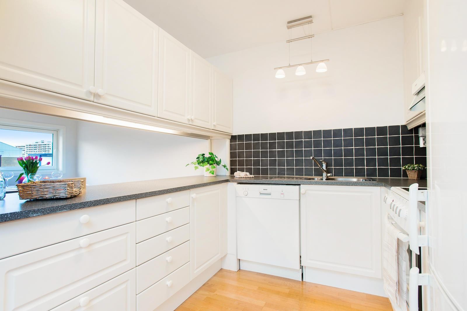 Praktisk åpen kjøkkenløsning med god benkeplass og lys innredning med malte, profilérte fronter. Galleribilde