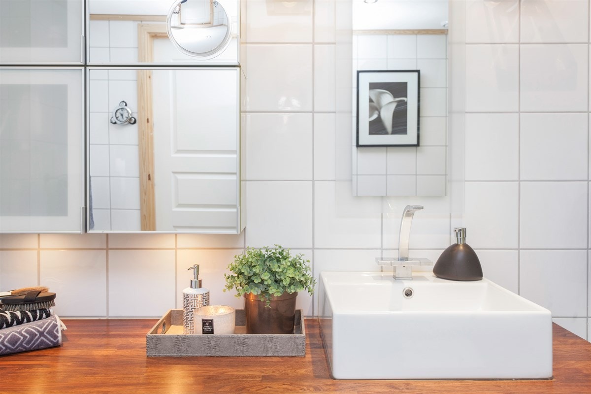 Midt i rommet møtes du av en stilig, original innredning med moderne, frittstående servant med tilhørende vannkran. Innredningen har både god benkplass og skapplass. Med varmekabler på flislagt gulv sikrer man seg en god start på dagen. Galleribilde