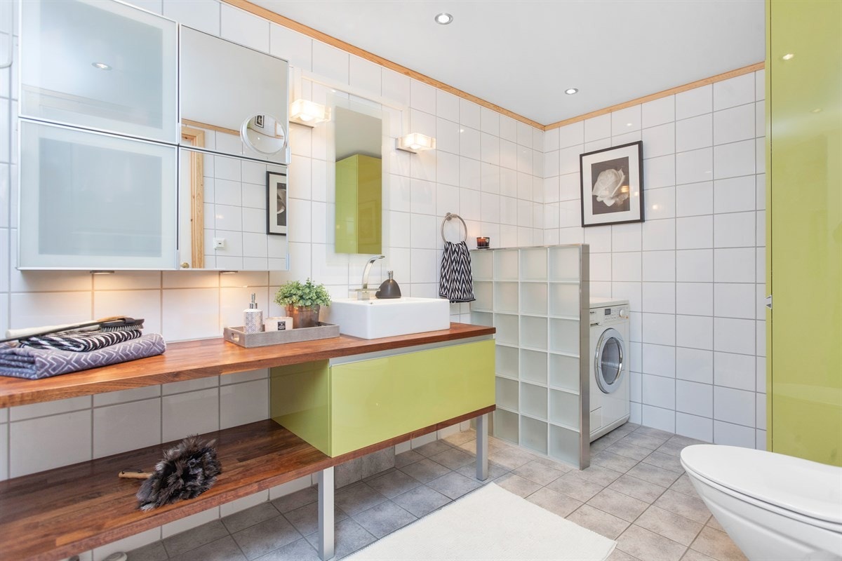 Stort og delikat bad som har en praktisk innredning i flere soner. Innerst finnes en sone for klesvask, den er praktisk innredet med høyskap for oppbevaring av renholdsutstyr og håndklær eksempelvis. Galleribilde