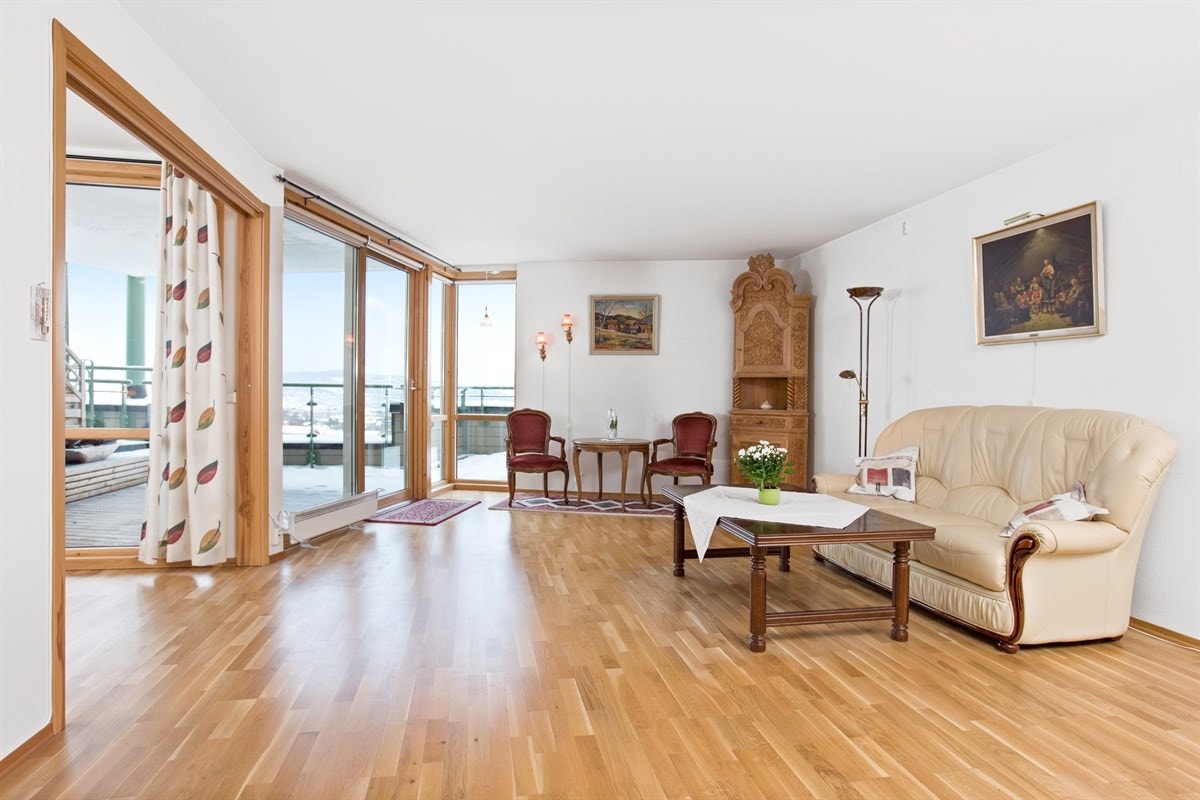 PROA Eiendomsmegling - Fra stuen har man en fantastisk utsikt mot byen og Trondheimsfjorden. Store vindusflater fra gulv til himling i stuen som ivaretar utsikten og gir stuen rikelig med innlys. Galleribilde
