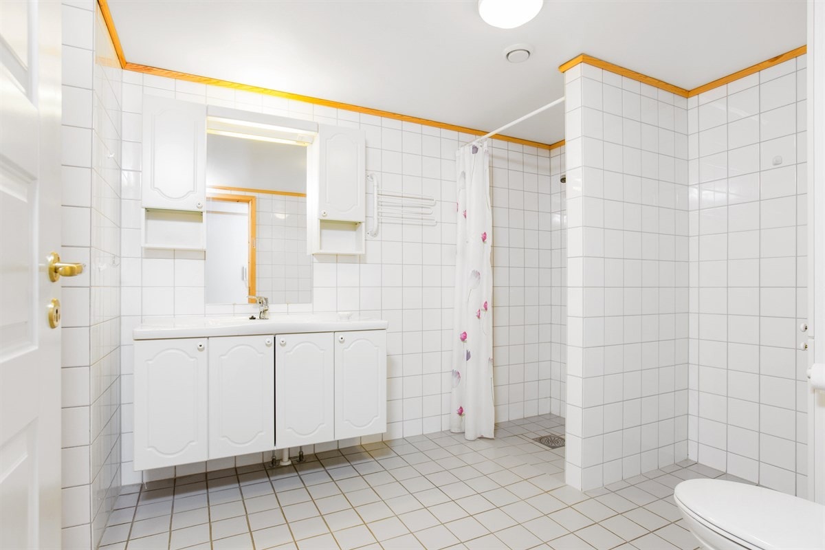PROA Eiendomsmegling - Pent flislagt bad med varme i gulv. Baderomsmøblene inkluderer servant med overskap, dusjnisje og wc. Galleribilde