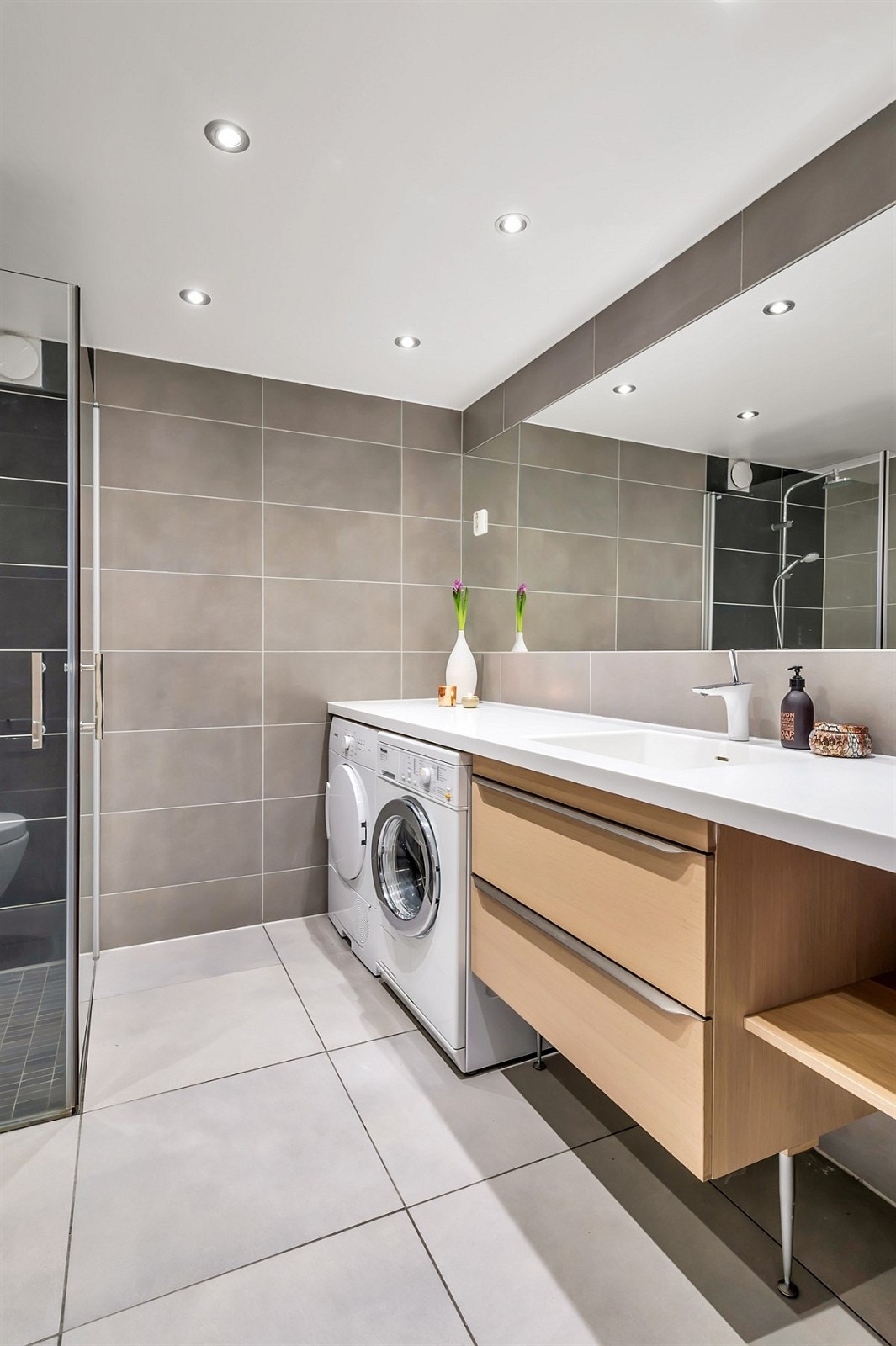 Badet har en stilren og moderne utførelse. Det er opplegg for vaskemaskin og tørketrommel. Galleribilde