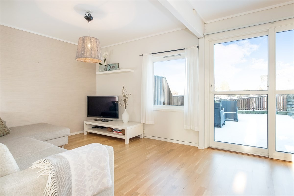 Det er utgang fra stuen til en stor solrik terrasse og hage. Her sitter du lunt og skjermet og terrassen har vært en kjærkommen del av boligen Galleribilde