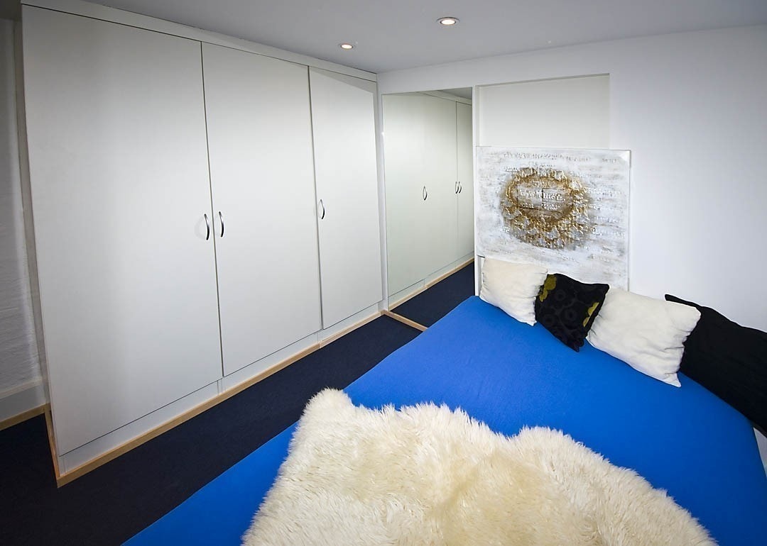 Rom nummer 3 er litt mindre, og har en 120 cm dobbeltseng. Derimot har dette rommet formidabel garderobeplass, med tre høye skap og en integrert bokhylle. I taket er dimbare innfelte downlights, og på gulvet en kombinasjon av teppe og parkett. Galleribilde