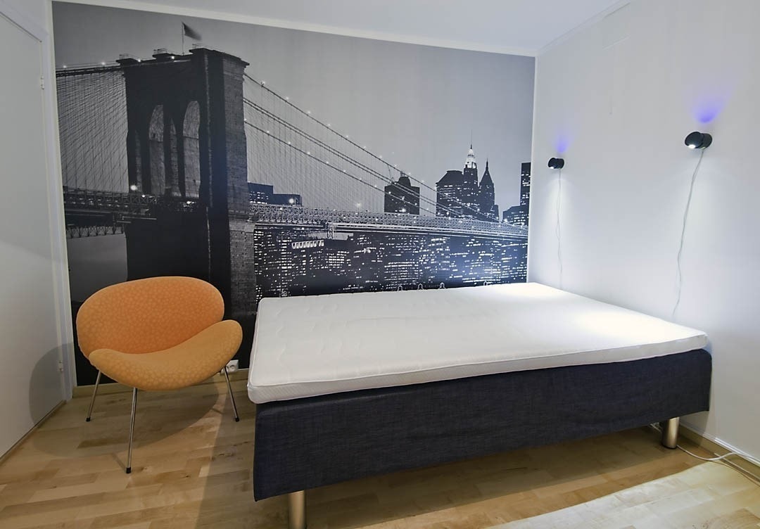 Rom nummer 2 har ny og elegant kontorpult med skuffer og skap, et stort romslig kleesskap og queen size dobbeltseng. Ene veggen er en fototapet med storby-motiv og i taket henger en veldig spesiell designlampe. Her er også stort vindu ut til hage, med rul Galleribilde