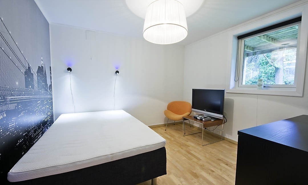 Rom nummer 2 har ny og elegant kontorpult med skuffer og skap, et stort romslig kleesskap og en queen size dobbeltseng. Ene veggen er en fototapet med storby-motiv og i taket henger en veldig spesiell designlampe. Her er også stort vindu ut til hage, med Galleribilde