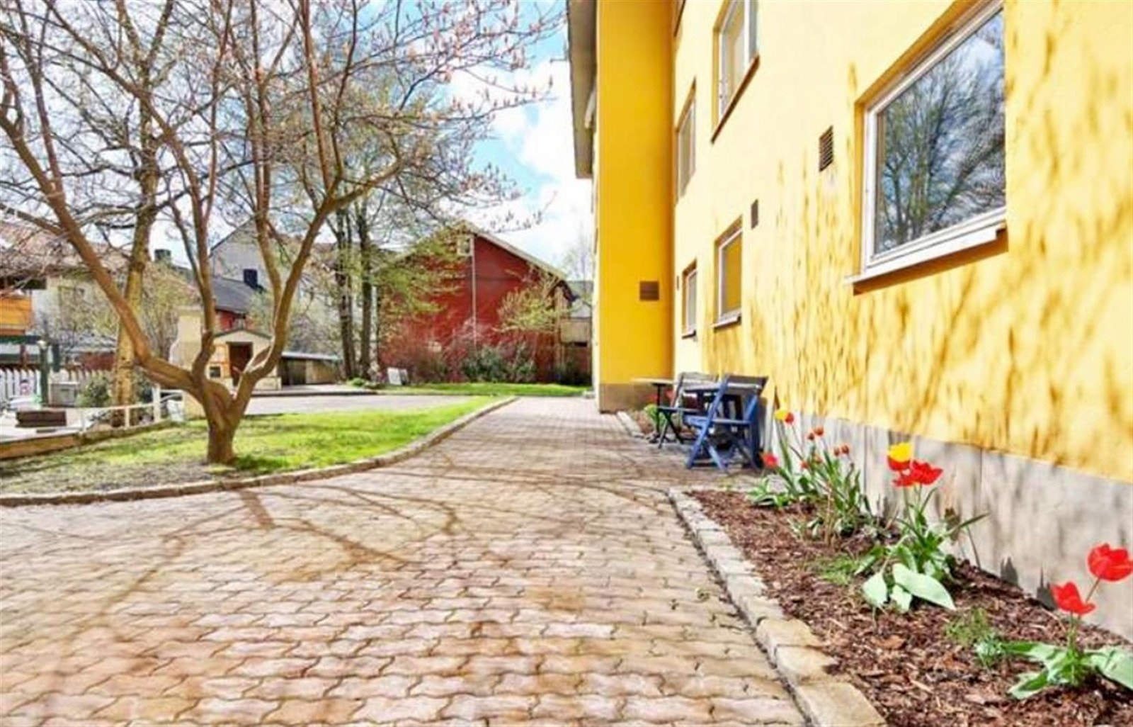 Pent opparbeidet bakgård med belegningstein, trær og beplantning Galleribilde