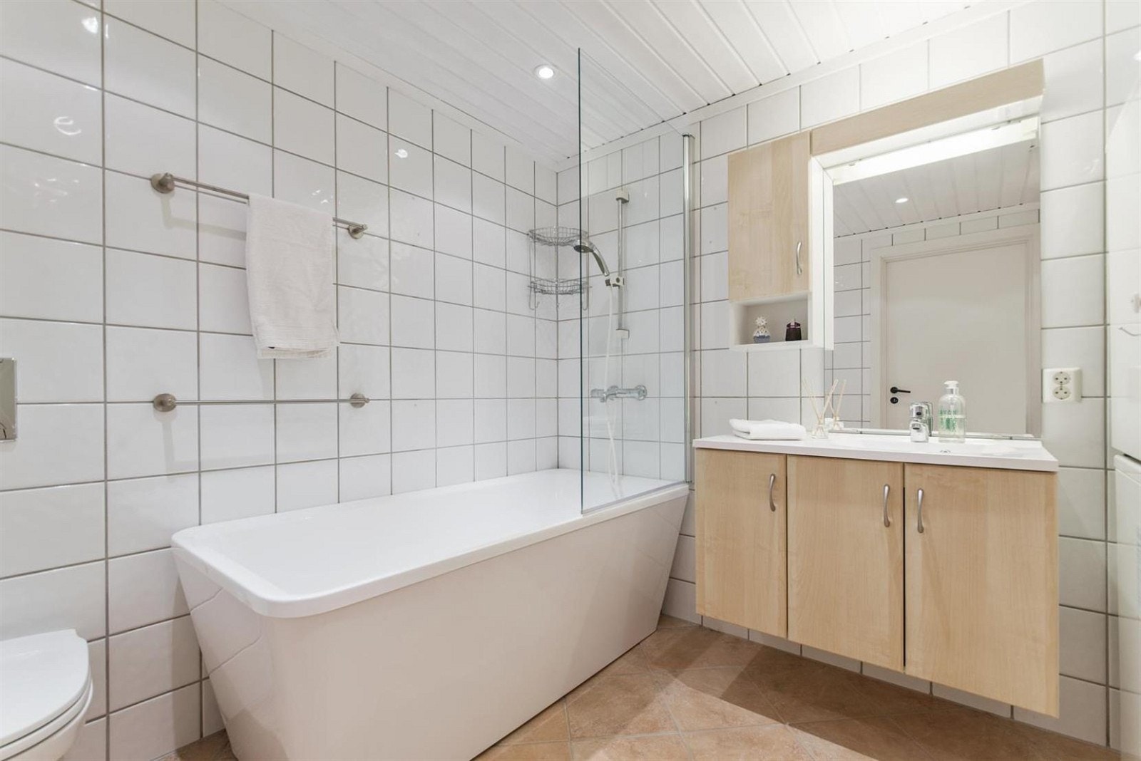 Stort bad med badekar, veggmontert wc og opplegg for vaskemaskin og tørketrommel. Galleribilde