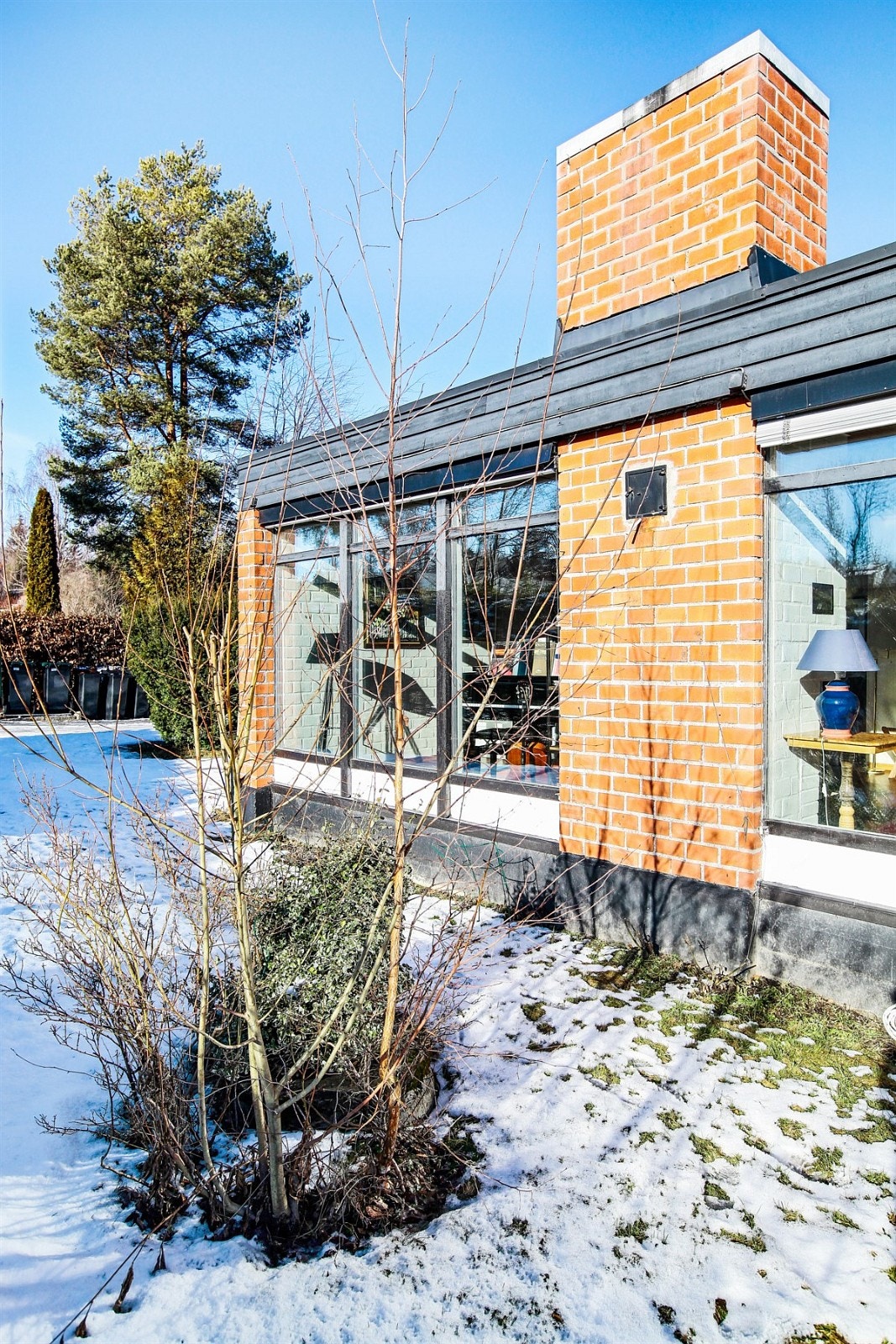 Opparbeidet hage, store vinduer inn til stue med peis. Galleribilde