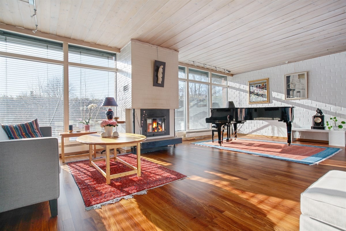 Stor og lys stue med vinduesflater fra gulv til tak. Usjenert og med peis. Utsyn, men ikke innsyn. Galleribilde