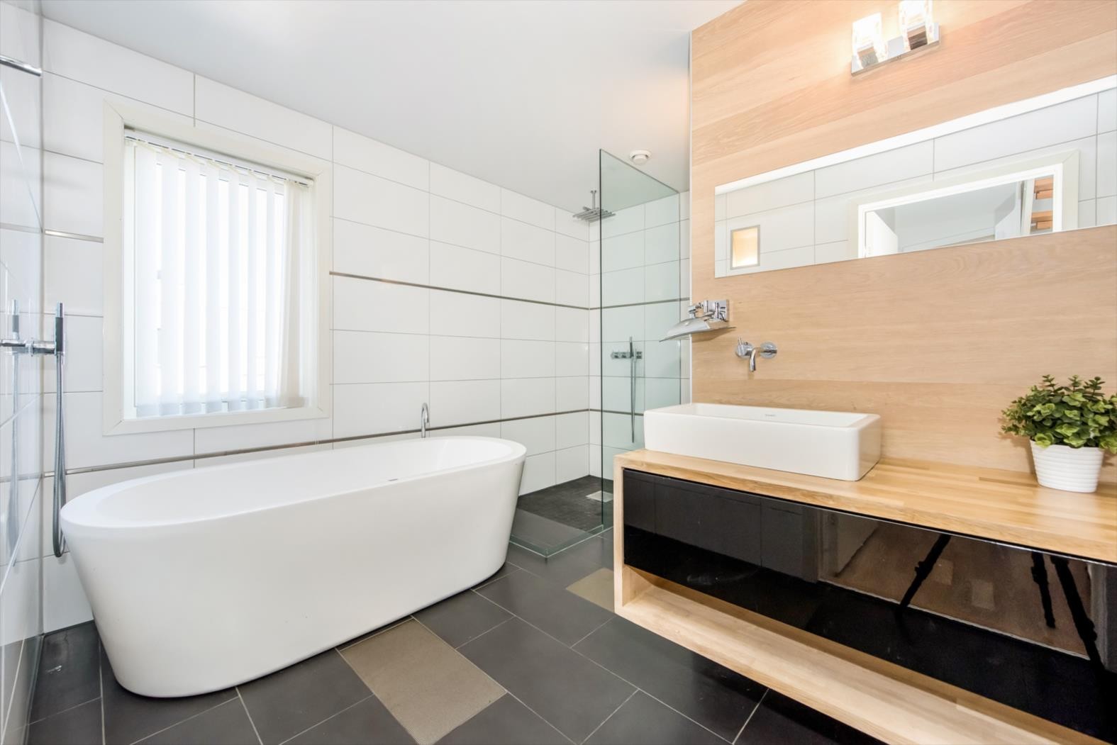 Badet er innredet med spesialdesignet baderomseksjon i heltre kombinert med sort høyglans, frittstående badekar, dushjørne med glassdører og vegghengt toalett. Galleribilde