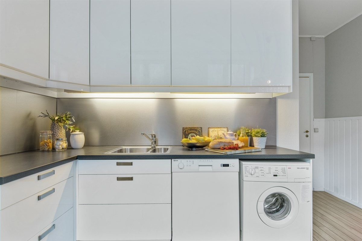 Det er opplegg til vaskemaskin og oppvaskmaskin under kjøkkenbenk. Galleribilde