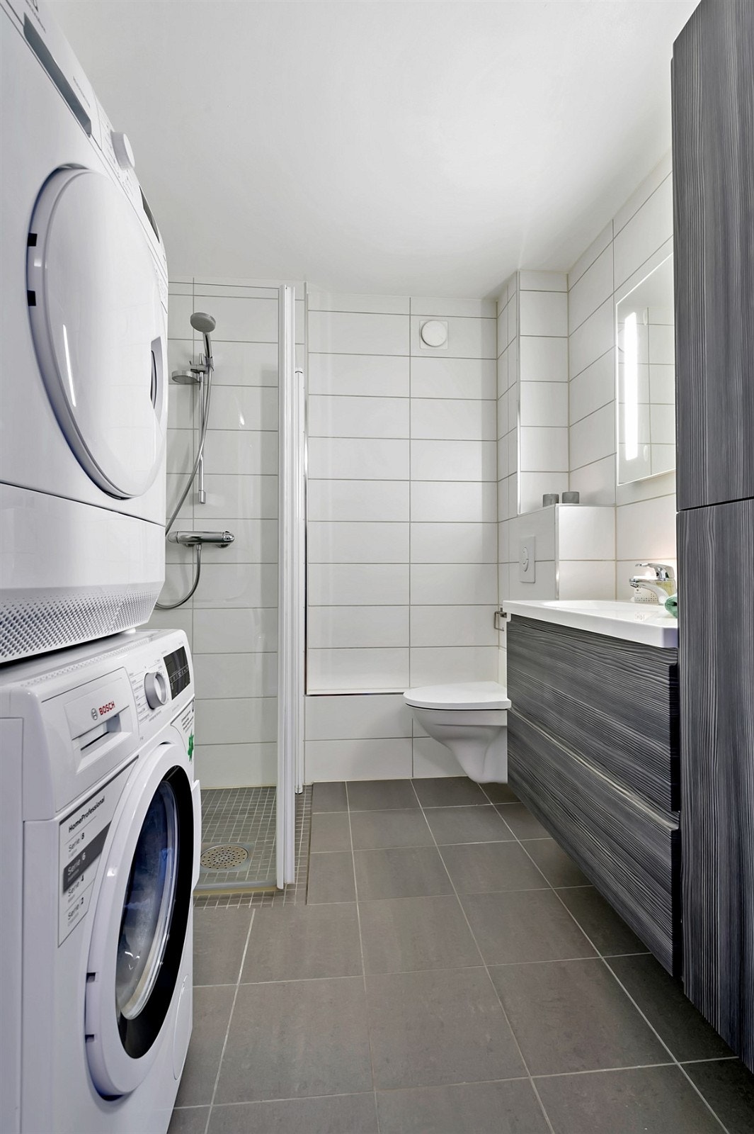 Badet er innredet med dusj med innfellbare glassdører, vegghengt toalett, servant med innredning, samt skap. Galleribilde