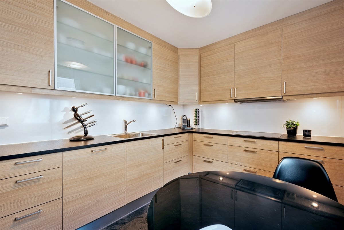 Kjøkkeninnredningen har eikfolierte fronter, 2 overskap med glassfronter og laminat benkeplate. Galleribilde