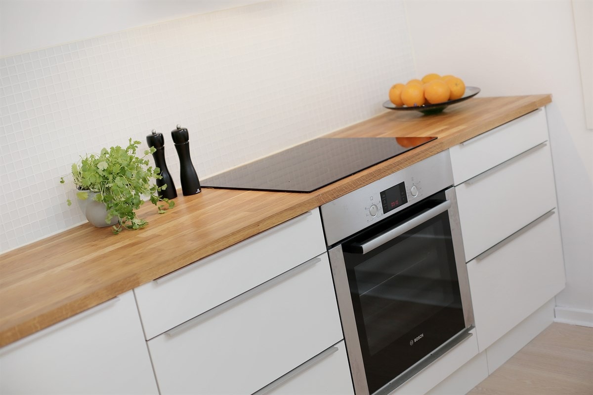 Kjøkkeninnredningen er stilren med glatte fronter og heltre eik benkeplate. Både oppvaskmaskin, stekeovn og koketopp er integrert. Galleribilde