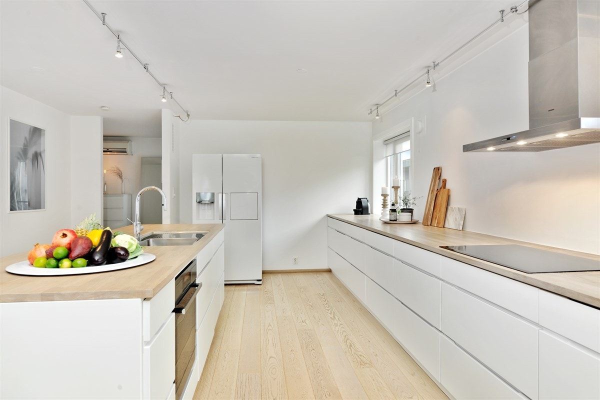 Lekkert kjøkken med mye skapplass og stor arbeidsbenk Galleribilde